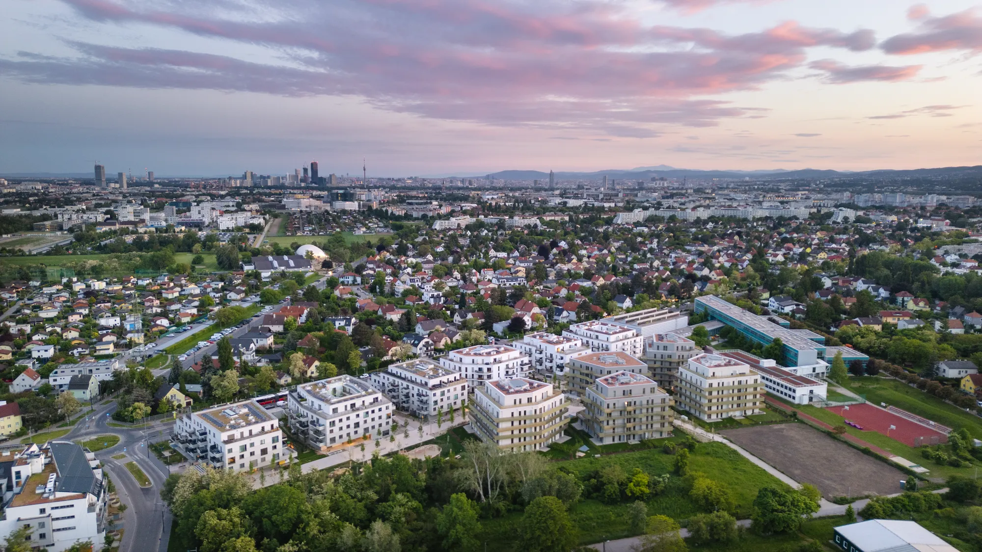 Luftaufnahme eines Wohngebiets in Wien bei Sonnenuntergang mit Blick auf die Skyline