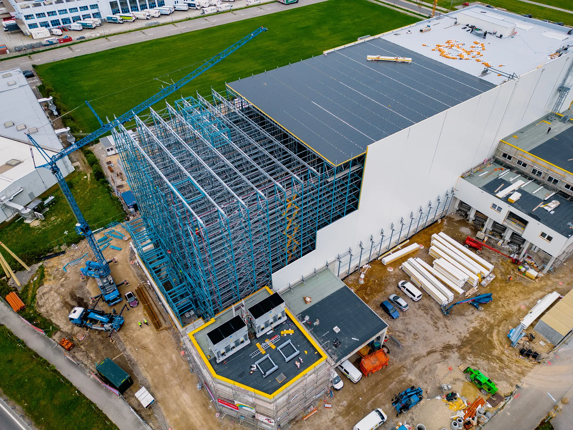 Drohnenaufnahme einer Industriebaustelle mit Lagerhalle und Kran aus der Vogelperspektive